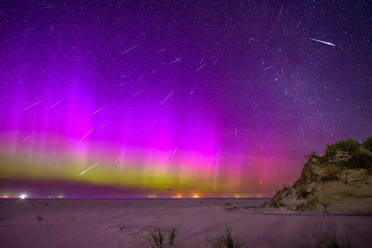 An aurora with meteor streaks over a beach
